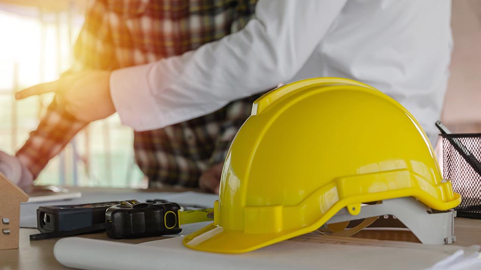 yellow safety helmet on workplace desk with construction worker